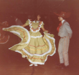 Mexican woman in green Jalisco dress dancing with Mexican man in gray Jalisco suit and sombrero